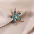 Detailed close-up of a sparkling multi-color rhinestone starfish brooch on satin fabric. - Blue Starfish