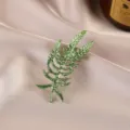 Detailed macro view of an elegant green leaf enamel brooch on textured champagne silk - Emerald Green Textured Leaf (663#)