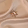 Detailed view of a gold-toned snowflake brooch featuring elegant white pearls on silk. - Gold