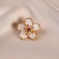 Macro view of an elegant cherry blossom brooch featuring sparkling pink rhinestones - Daisy / White