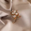 Detailed close-up of the elegant floral bouquet brooch featuring mother-of-pearl petals and pearls. - Bouquet / Gold