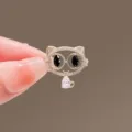 Close-up of a delicate hollow cat brooch featuring black eyes and a pink crystal drop - Cat Style
