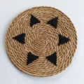 Top-down view of a round woven straw placemat with black triangular patterns - 30cm / Black Embroidery