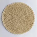 Primo piano dettagliato di una tovaglietta rotonda beige intrecciata con bordo ondulato. - Beige