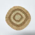 Gros plan de décoration murale en paille tissée artisanale avec motif spiralé et franges. - Massette Carrée