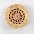 Detail of bohemian straw wall hanging, featuring raffia fringe and geometric spiral design. - C6