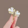 Detailed macro view of elegant gold flower brooch with white pearls and rhinestones - Two Flowers