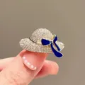 Detailed view of a sparkling sun hat brooch with crystals and a blue enamel bow - 302# Hat