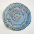 Mantel individual redondo tejido nórdico con un vibrante diseño de espiral azul y amarillo - Azul Teñido Satinado