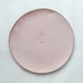 Vista ravvicinata di una tovaglietta rotonda tessuta in rosa con bordo pompon, cucina accogliente. - 38 cm / Rosa