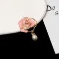 Close-up of elegant pink enamel camellia flower brooch with pearl pendant for suit coat pin. - Pink