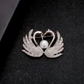 Elegant double swan heart-shaped brooch with sparkling crystals and a central white pearl - Double Swan Style
