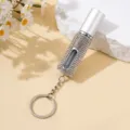 Gros plan d'un atomiseur de parfum 5ml orné de strass avec porte-clés sur fond jaune pastel. - 5ml / Blanc