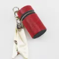 Detail shot of a red rhinestone-studded lipstick pouch keychain with a silk scarf accessory - Red