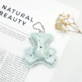 Macro detail of a sparkling mint green leather bear keychain with crystal studs. - Cyan