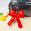 Vista dettagliata di un ciondolo per borsa a fiocco rosso in pelle PU su una borsa nera - Rosso