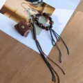Close-up of vintage leather bag charm keychain with leopard beads and heart carabiner - Coffee
