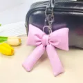 Vista ravvicinata di un grazioso portachiavi a fiocco in pelle PU rosa su una borsa nera - Rosa