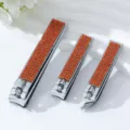 Detailansicht von silbernen Nagelknipsern aus Edelstahl mit orangefarbenen Strasssteinen - Dreiteiliges Set / Orangerot