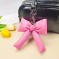 Dettaglio ravvicinato di un ciondolo a fiocco rosa imbottito con gancio argento - Rosso rosa