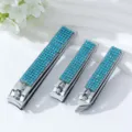 Detailansicht von drei mit blauen Strasssteinen verzierten Nagelknipsern aus Edelstahl - Dreiteiliges Set / Seeblau