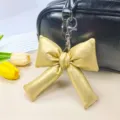 Un pendentif porte-clés en forme de nœud doré suspendu à un sac à main en cuir noir chic - Jaune