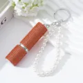 Detail of a 5ml orange rhinestone perfume atomizer keychain with elegant white pearls. - Orange Red