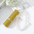 Detail view of a 5ml golden rhinestone perfume atomizer with elegant pearl strap keychain - Yellow