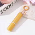 Vista detallada de un elegante atomizador de perfume dorado de 5 ml con llavero de lazo. - Dorado