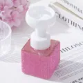 Detailed view of pink rhinestone soap dispenser with elegant white flower foam pump. - Pink