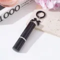 Primer plano de un frasco pulverizador de perfume negro de 5ml con un lazo decorativo. - Negro