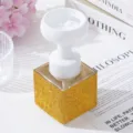 Close-up of luxury gold rhinestone foaming bottle with white flower pump head - Yellow