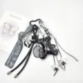 Detailed view of a handmade black leather bear keychain with shiny silver charms. - Black