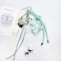 Close-up of a sweet pastel key chain with mint green leather puppy charm and white ribbon - Cyan
