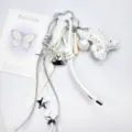 Detail view of white leather bear, baseball bat, and silver heart charms on a keychain - White