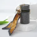 Luxury luxury rhinestone lipstick bag keychain with elegant silk scarf on white stone props. - Gray