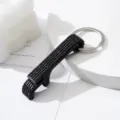 Close-up detail of a luxury black rhinestone-encrusted aluminum bottle opener keychain. - Black