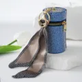 Close-up of a blue rhinestone lipstick holder keychain with an elegant silk scarf detail. - Blue