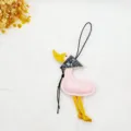 Detailed view of a pink leather duck bag charm featuring a patterned scarf and yellow legs - Pink