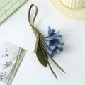 Detailed view of handcrafted blue leather flower bag charm with green leaves accessory - Blue