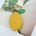 Detail view of a yellow lemon-shaped PU leather pouch with a green leaf and clip - Lemon Style
