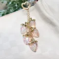 Detail view of shimmering resin strawberry charms on a gold heart-shaped keychain - Transparent Pink