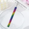 Close-up view of a rainbow rhinestone nail art pull-wire tool with fine metal tips - Colorful