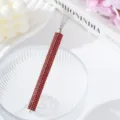 Detail showing the vibrant red rhinestone handle of the professional nail art line drawing tool. - Red