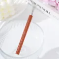 Close-up detail of nail art drawing pen with orange rhinestones and fine wire tips - Orange Red