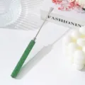 Close-up of a stainless steel nail mixing spatula with a sparkling green rhinestone handle - Green