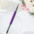 Close-up of double-ended nail art brush with purple rhinestone handle and fine liner tip. - Deep purple