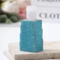 Close-up detail of a travel spray bottle covered in sparkling blue rhinestones - 30ml / Lake Blue