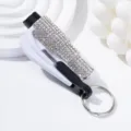 Close-up of a white rhinestone car safety hammer featuring window breaker and seatbelt cutter. - White