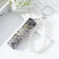 Detail view of a 5ml sparkling rhinestone perfume atomizer with pearl keychain strap - Black Gold Silver Gradient